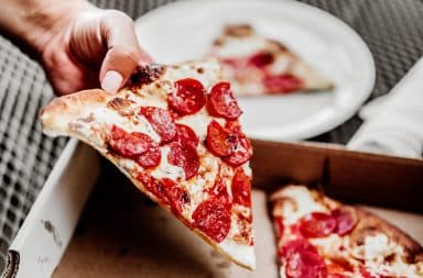 Slice of pepperoni pizza in hand