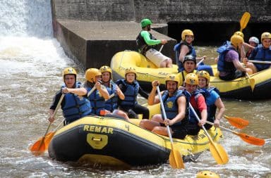 White water rafting guide in a boat with paddlers